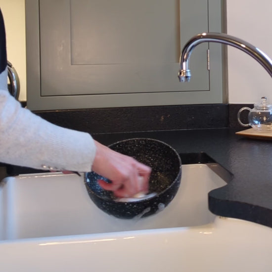 woman scrubbing pan with pot scrubbing brush